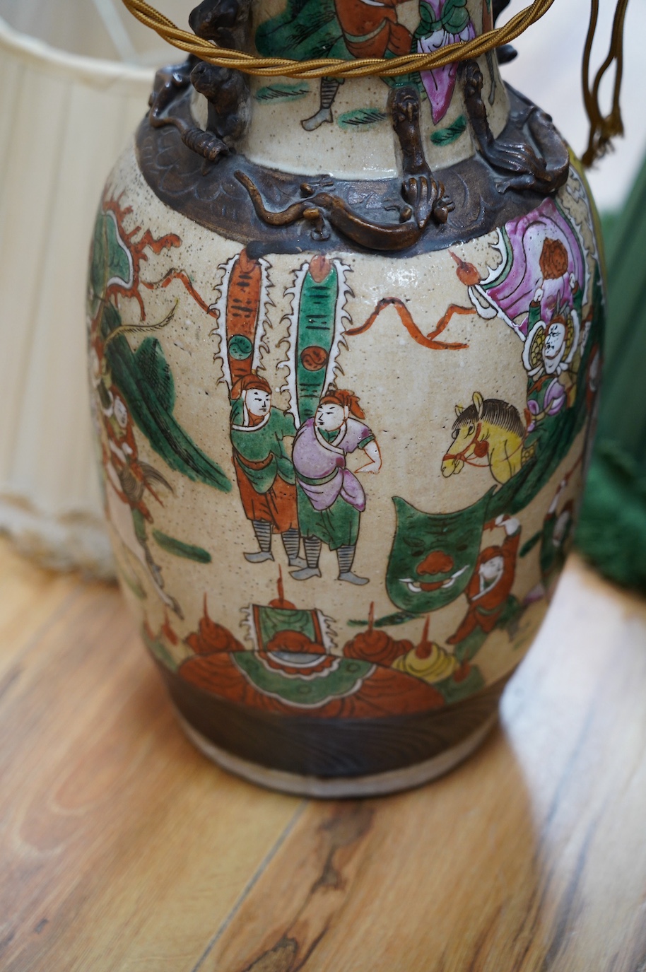 A pair of early 20th century Chinese famille verte crackle glaze ‘warrior’ vases converted to lamps with shades, height 44cm. Condition - fair to good